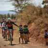 Deelnemers Africa Classic deelt vanaf de fiets high fives uit aan juichende kinderen
